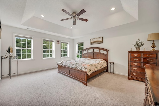 carpeted bedroom featuring ceiling fan and a raised ceiling