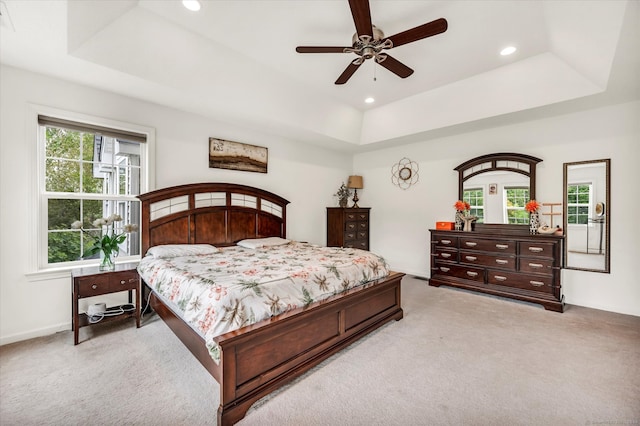 carpeted bedroom featuring ceiling fan and a raised ceiling