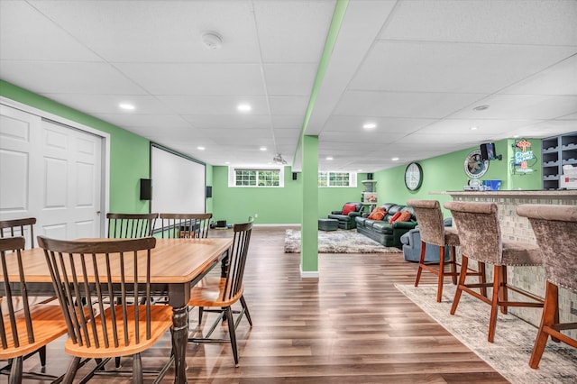 dining area with a drop ceiling, bar area, and hardwood / wood-style floors