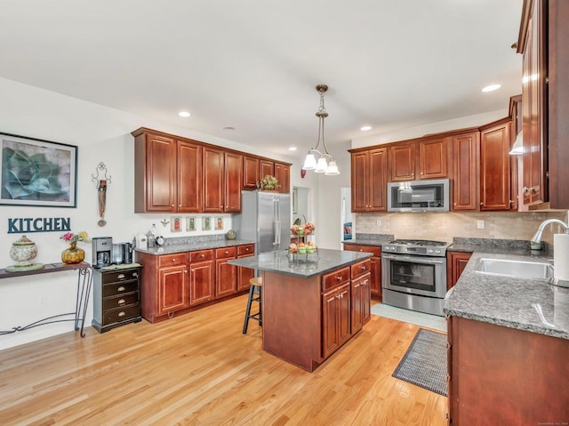 kitchen with a center island, sink, a kitchen bar, light hardwood / wood-style flooring, and appliances with stainless steel finishes