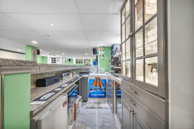 kitchen featuring light stone countertops, a drop ceiling, dishwasher, and plenty of natural light