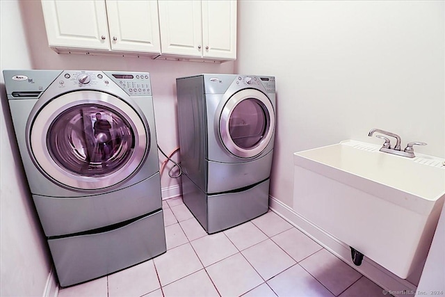 laundry area with cabinets, sink, light tile patterned flooring, and washing machine and clothes dryer