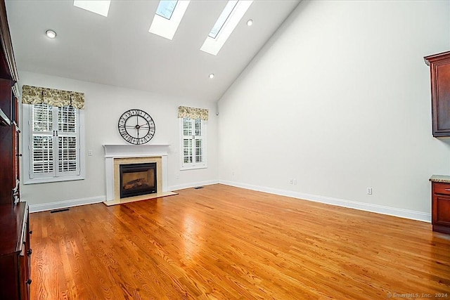 unfurnished living room featuring light wood-type flooring, high vaulted ceiling, a wealth of natural light, and a premium fireplace