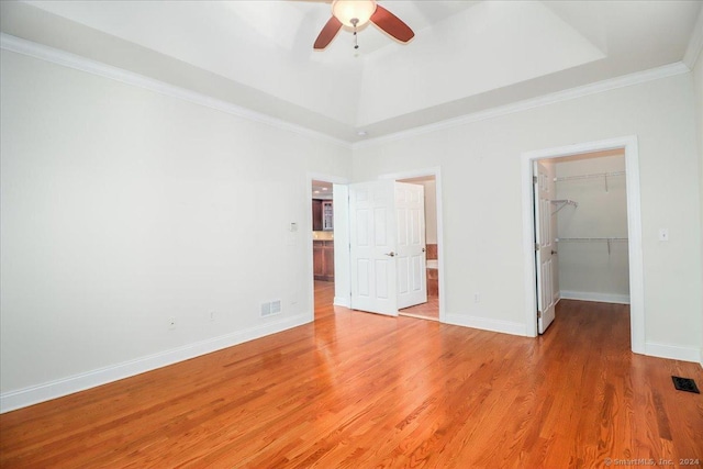 unfurnished bedroom with hardwood / wood-style flooring, ceiling fan, a spacious closet, ornamental molding, and a closet