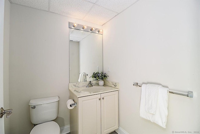 bathroom with vanity, toilet, and a drop ceiling