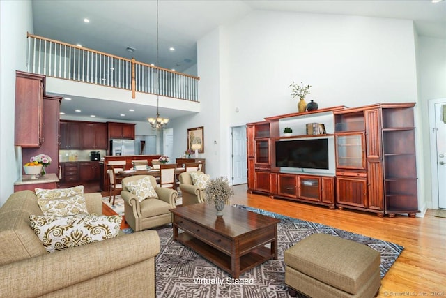 living room with hardwood / wood-style flooring, a notable chandelier, and high vaulted ceiling