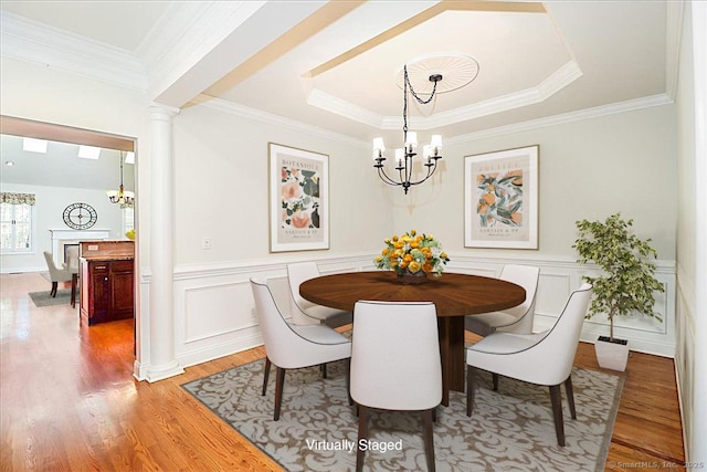 dining area featuring decorative columns, ornamental molding, hardwood / wood-style floors, and a notable chandelier