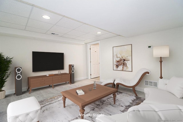 carpeted living room featuring a drop ceiling