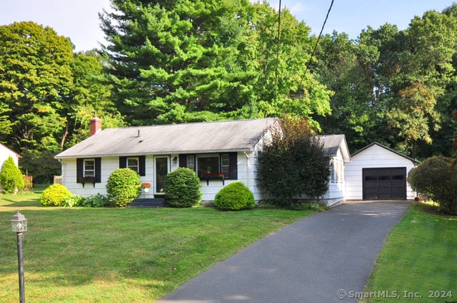 single story home with a front yard, a garage, and an outbuilding