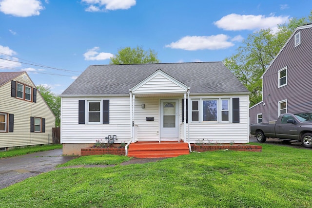 bungalow featuring a front lawn and a shingled roof
