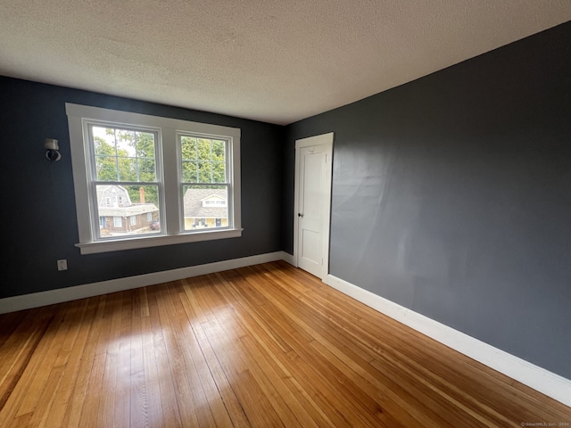 empty room with a textured ceiling and light wood-type flooring