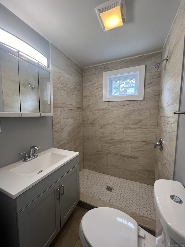 bathroom featuring tiled shower, vanity, and toilet