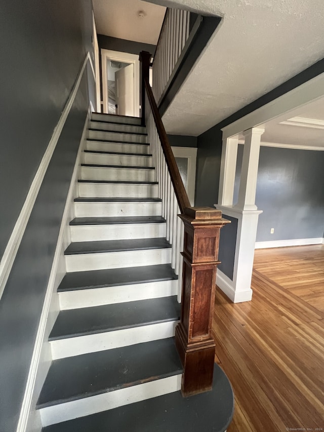 stairs featuring ornate columns and hardwood / wood-style floors