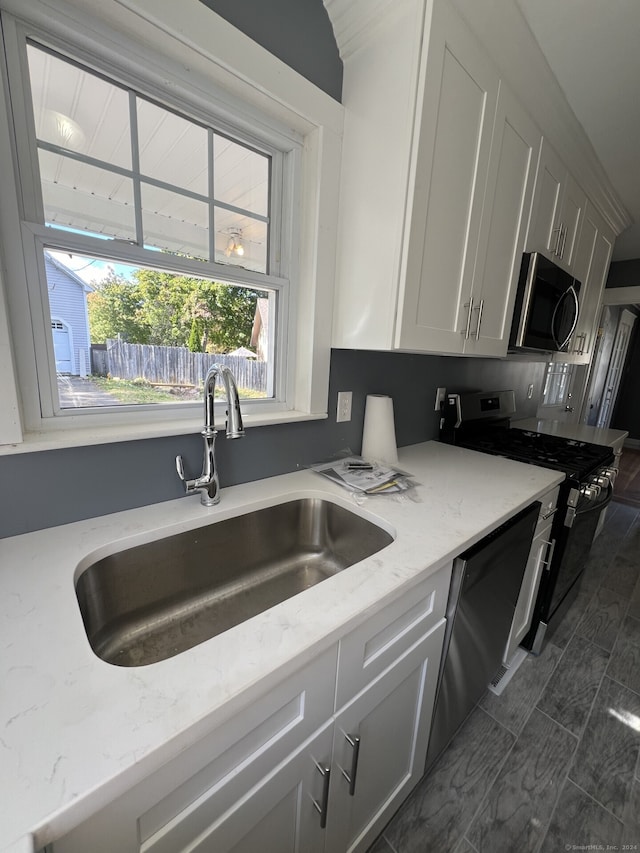 kitchen featuring light stone counters, sink, white cabinetry, and black appliances