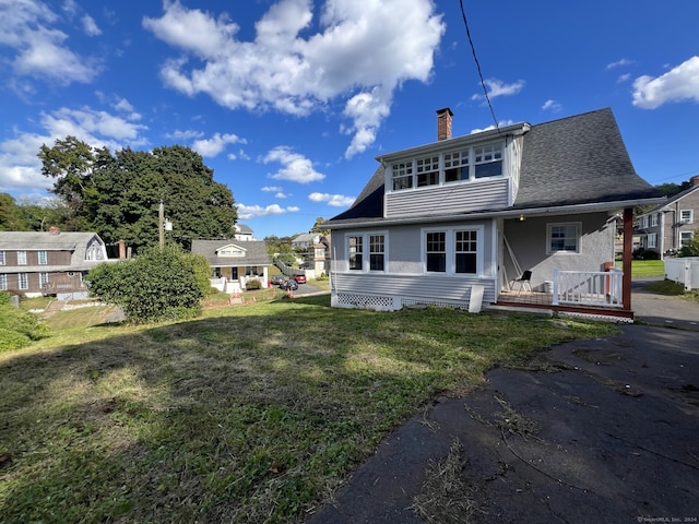 back of house featuring a lawn and a porch