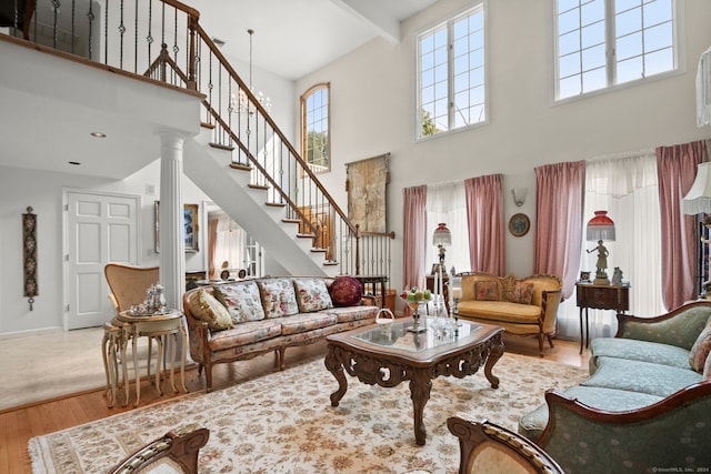 living room featuring hardwood / wood-style flooring, a towering ceiling, and ornate columns