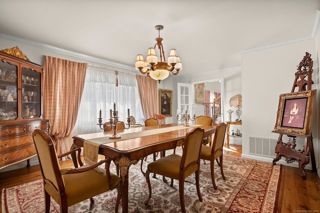 dining room with a notable chandelier, hardwood / wood-style flooring, and crown molding