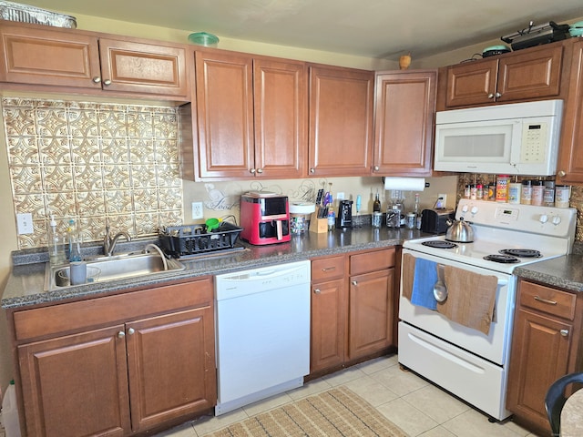 kitchen with decorative backsplash, white appliances, light tile patterned floors, and sink