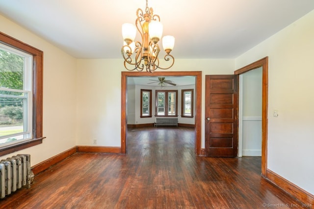 spare room featuring ceiling fan with notable chandelier, radiator heating unit, and plenty of natural light