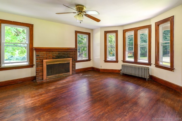 unfurnished living room featuring ceiling fan, radiator, a fireplace, and dark hardwood / wood-style floors