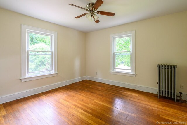 unfurnished room with radiator, hardwood / wood-style floors, and ceiling fan