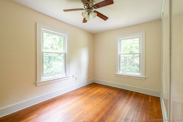 unfurnished room featuring ceiling fan, hardwood / wood-style flooring, and a healthy amount of sunlight