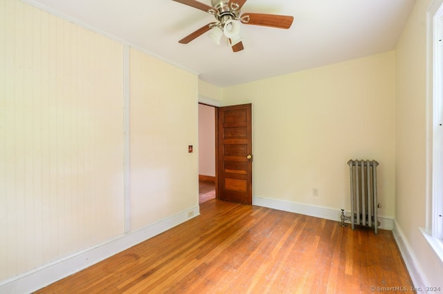 spare room featuring ceiling fan, wood-type flooring, and radiator heating unit