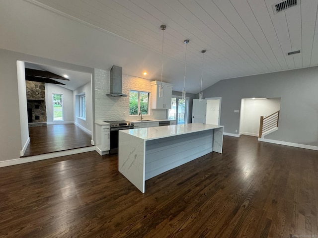 kitchen featuring white cabinetry, wall chimney exhaust hood, stainless steel appliances, pendant lighting, and vaulted ceiling