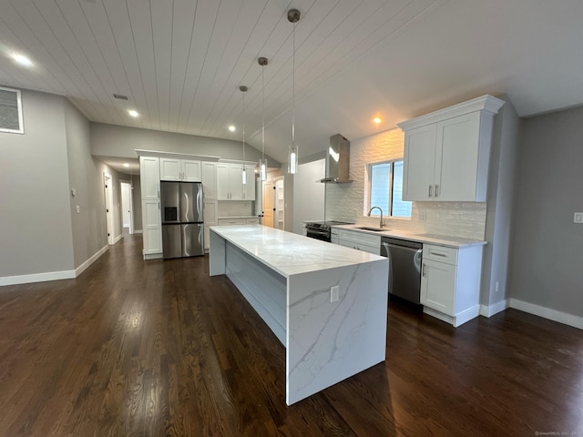 kitchen with appliances with stainless steel finishes, tasteful backsplash, wall chimney range hood, pendant lighting, and a kitchen island