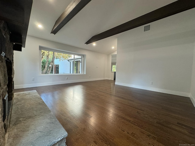 unfurnished living room with lofted ceiling with beams, dark hardwood / wood-style floors, and a stone fireplace