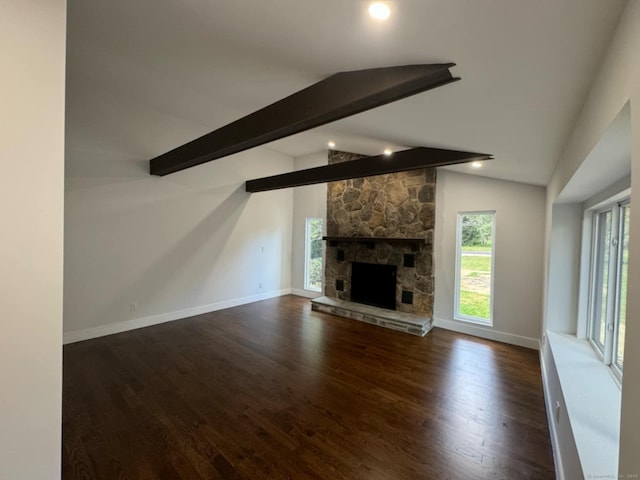 unfurnished living room featuring vaulted ceiling with beams, a stone fireplace, a wealth of natural light, and dark wood-type flooring