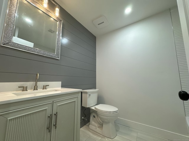 bathroom featuring tile patterned floors, vanity, toilet, and wooden walls