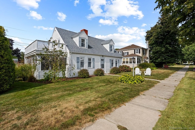 cape cod home featuring a balcony and a front yard