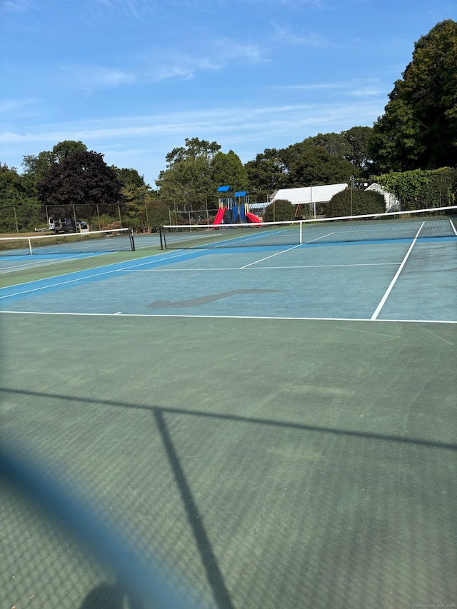 view of tennis court featuring a playground