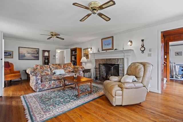 living room with light hardwood / wood-style floors, crown molding, a fireplace, and ceiling fan