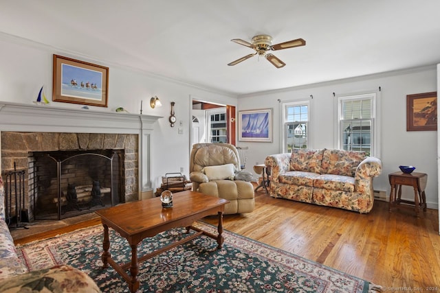 living room featuring crown molding, a fireplace, ceiling fan, and hardwood / wood-style flooring