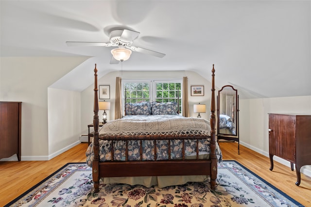 bedroom with light wood-type flooring, vaulted ceiling, a baseboard heating unit, and ceiling fan