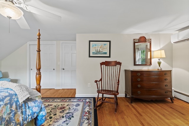 bedroom featuring light hardwood / wood-style floors, baseboard heating, and ceiling fan