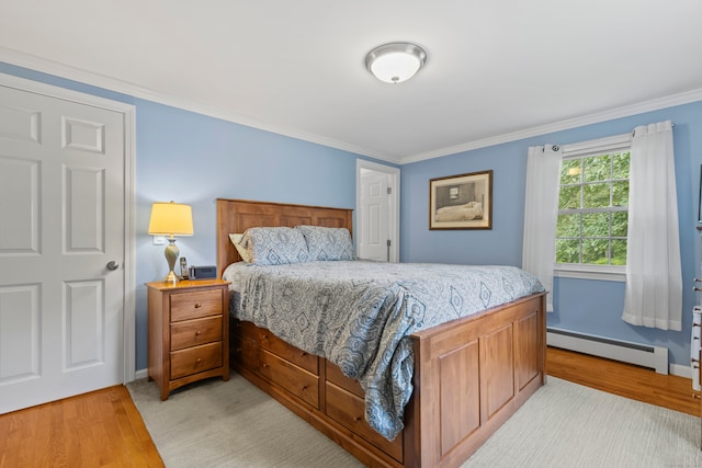 bedroom with light hardwood / wood-style flooring, crown molding, and a baseboard heating unit