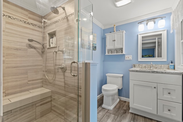 bathroom with vanity, hardwood / wood-style floors, ornamental molding, toilet, and a shower with door