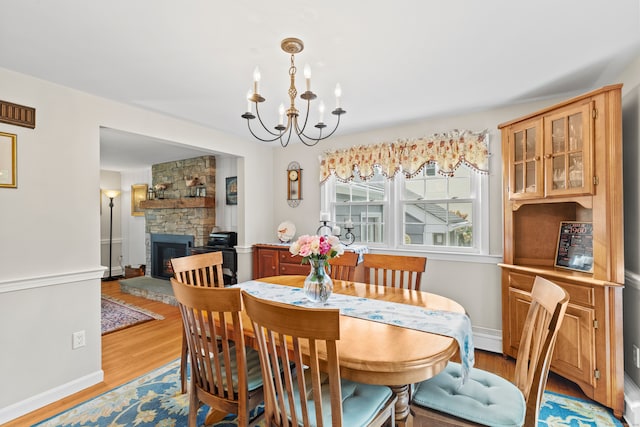 dining area featuring a fireplace, light hardwood / wood-style flooring, and a notable chandelier