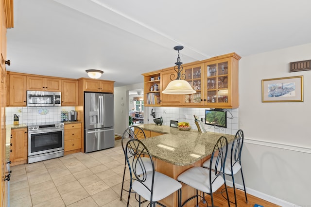 kitchen featuring hanging light fixtures, kitchen peninsula, backsplash, stainless steel appliances, and light stone countertops