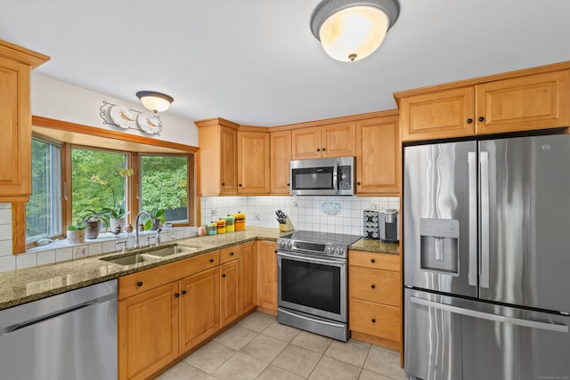 kitchen featuring dark stone counters, tasteful backsplash, sink, stainless steel appliances, and light tile patterned floors