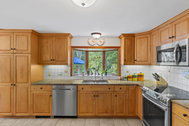 kitchen featuring light stone counters, light tile patterned floors, appliances with stainless steel finishes, and sink