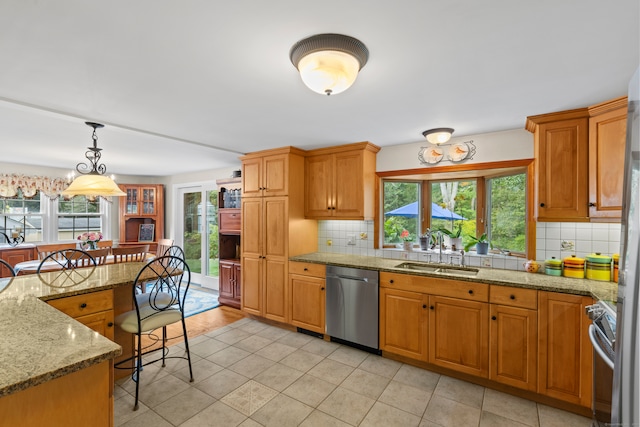 kitchen featuring backsplash, appliances with stainless steel finishes, hanging light fixtures, and sink