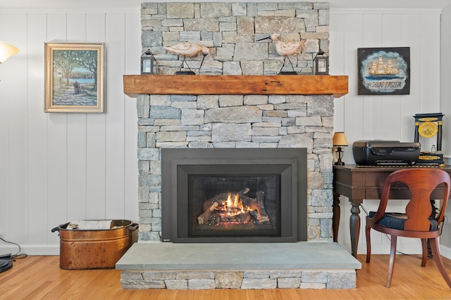 details with a stone fireplace, ornamental molding, and hardwood / wood-style flooring