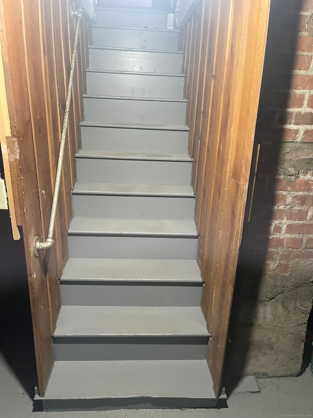 staircase featuring brick wall