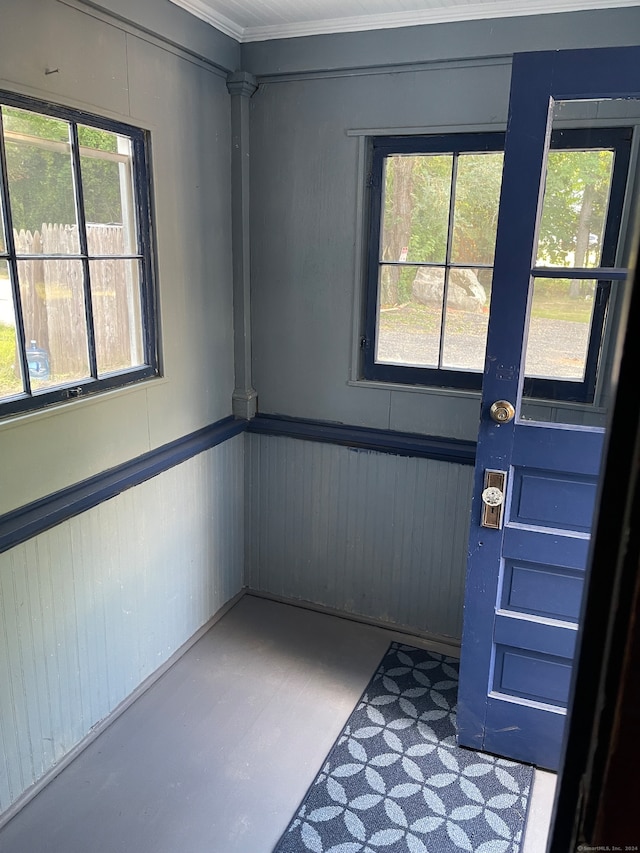 doorway to outside with ornamental molding, concrete flooring, and a healthy amount of sunlight