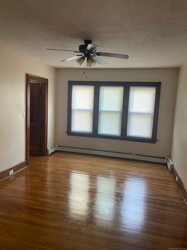 empty room featuring wood-type flooring, a textured ceiling, and a baseboard heating unit