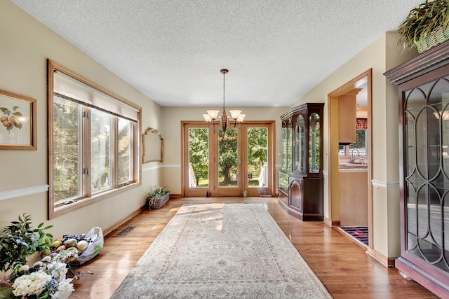 interior space with a notable chandelier, light hardwood / wood-style flooring, and a textured ceiling